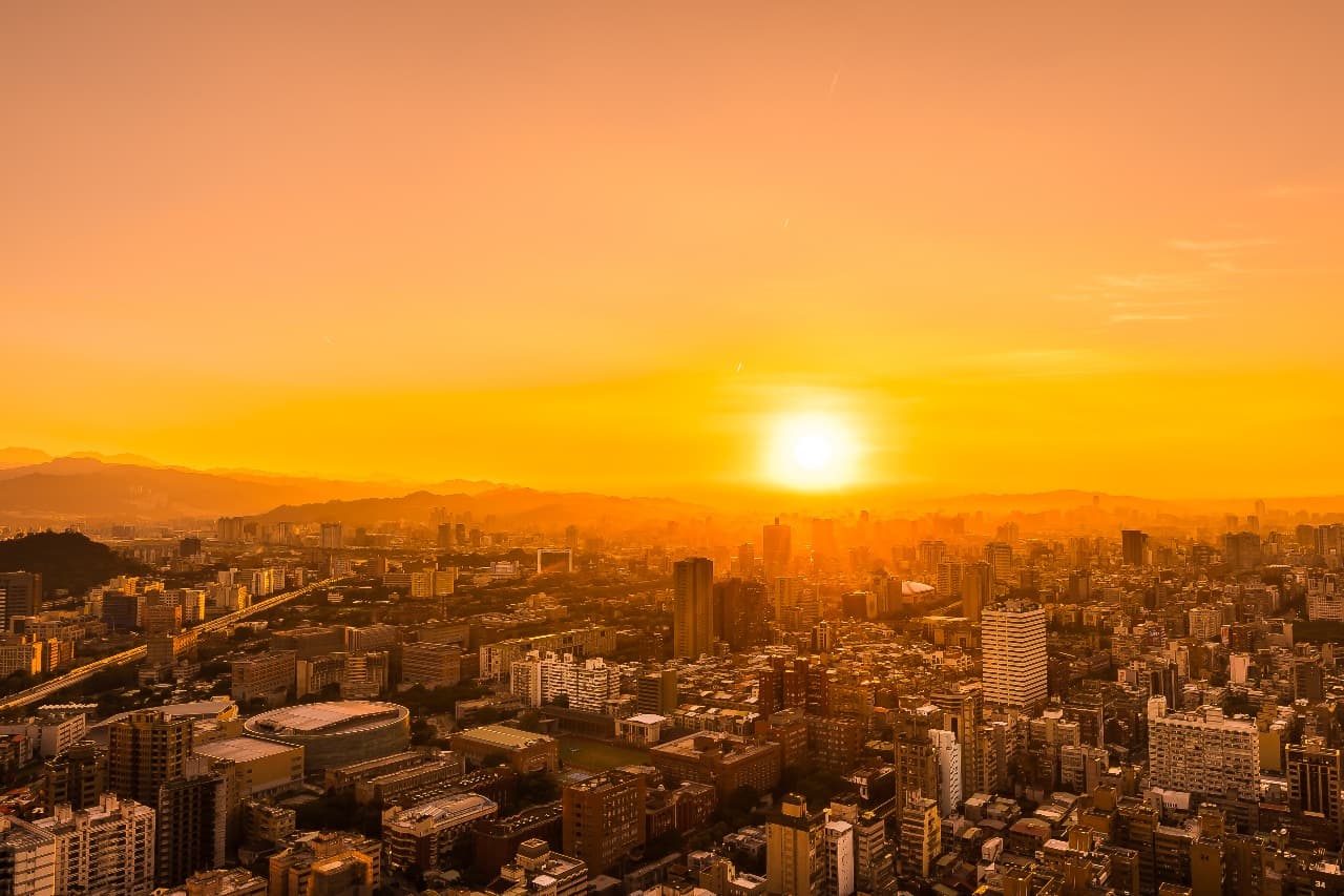 A modern city skyline at sunset, seen from a high-rise building.